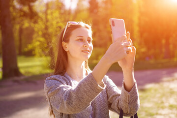  brunette woman with sunglasses is holding a phone, taking photos of herself