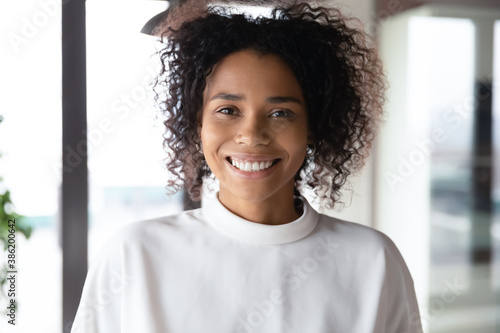 Close up head shot profile photo portrait of smiling attractive young african american businesswoman in office. Reliable financial consultant employee female executive manager looking at camera.
