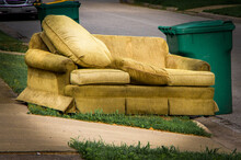 Old Yellow Couch With Cushions Sits On A Curb In Residential Area Next To A Recycling Cart Waiting For Bulk Waste Hauler Pickup On Trash Day