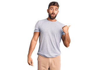 Young hispanic man wearing casual clothes surprised pointing with hand finger to the side, open mouth amazed expression.