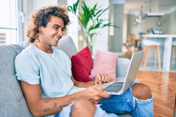 Young hispanic man smiling happy using laptop at home