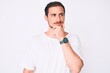 © Krakenimages.com - Young handsome man wearing casual white tshirt with hand on chin thinking about question, pensive expression. smiling with thoughtful face. doubt concept.
