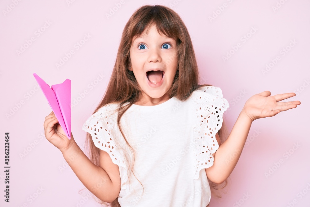 Little caucasian kid girl with long hair holding paper airplane ...