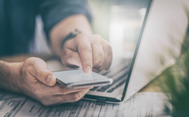 Wall Mural - Man works at home and uses a smart phone and notebook computer.