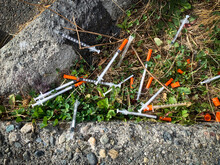 Hypodermic Needles Scattered On The Ground Near A Homeless Encampment