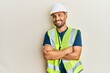 © Krakenimages.com - Handsome man with beard wearing safety helmet and reflective jacket happy face smiling with crossed arms looking at the camera. positive person.