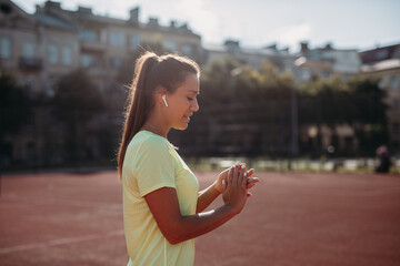 Wall Mural - Woman standing at stadium and taking rest between exercises