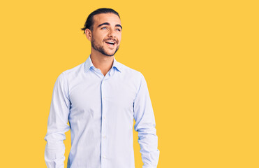 Young handsome man wearing business clothes looking away to side with smile on face, natural expression. laughing confident.