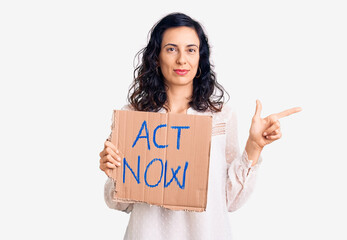 Wall Mural - Young beautiful hispanic woman holding act now banner smiling happy pointing with hand and finger to the side