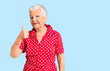 © Krakenimages.com - Senior beautiful woman with blue eyes and grey hair wearing a red summer dress doing happy thumbs up gesture with hand. approving expression looking at the camera showing success.