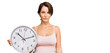 © Krakenimages.com - Young brunette woman with short hair holding big clock thinking attitude and sober expression looking self confident