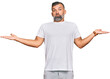 © Krakenimages.com - Middle age handsome man wearing casual white tshirt clueless and confused expression with arms and hands raised. doubt concept.