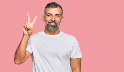 Wall Mural - Middle age handsome man wearing casual white tshirt showing and pointing up with fingers number two while smiling confident and happy.