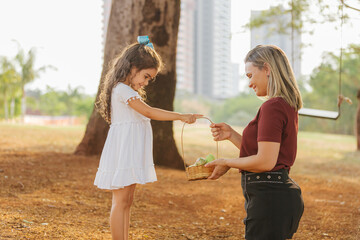 Wall Mural - Latin family celebrating Easter. Curly girl holds a hamper of easter eggs to give to her mother