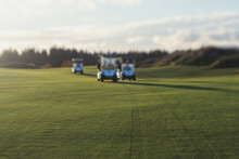 Golf Electric Cars Riding On A Golf Course In The Sunny Day, Golf Carts Drive With Golfers In Resort Club