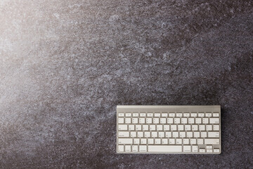 Top view flat lay of a modern white computer keyboard on office desk concrete background with copy space for text