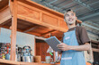 © Odua Images - Asian male seller in apron holding a tablet pc standing in side of the cart stall
