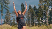 Free spirited hippie woman with hands up on sunny day alone in forest, slowmo