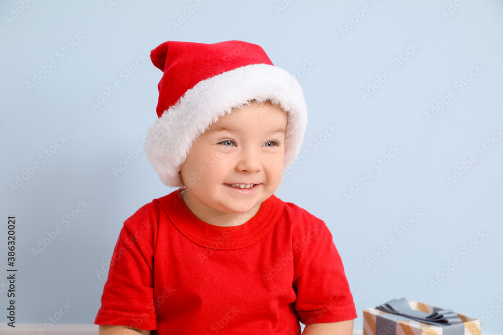 Cute little baby in Santa hat on color background