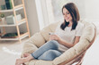 © deagreez - Photo of positive girl sit wicker chair read social media news on smartphone wear casual style clothes in house room