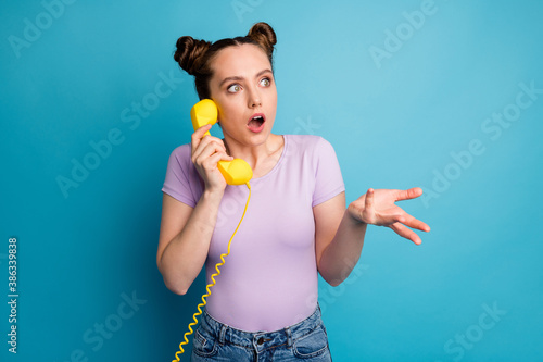 Really Photo of pretty lady two funny buns hold cable telephone handset speaking friends open mouth shocked last gossips wear casual purple t-shirt isolated blue color background