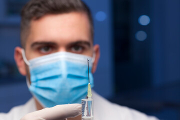 Close-up of doctor with medical mask preparing a syringe for vaccination