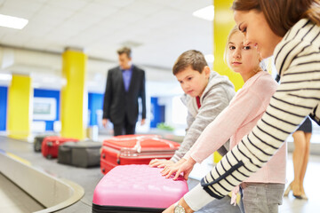 Wall Mural - Mother and children on the luggage belt in the airport