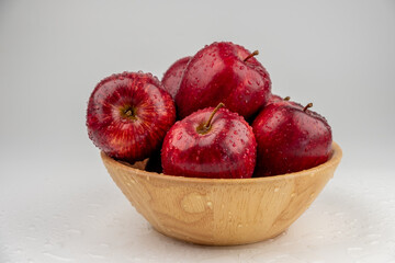 Pile of red apple in wooden bowl with clear water drop on 
shell surface texture pattern isolated, white background