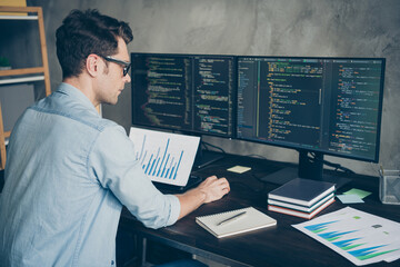 Profile side view portrait of his he nice attractive focused skilled guy geek coding programming writing database source at modern industrial interior loft concrete wall style work place station