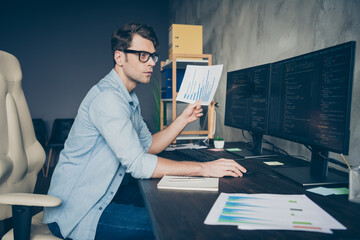 Profile side photo of focused concentrated guy manager sit desk look computer screen analyze decoding debugging operating system compare with data funds chart in workplace workstation