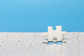 Wall Mural - Unfinished white jigsaw puzzle on blue background with copy space. Business strategy teamwork and problem solving concept.