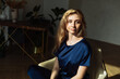 © etonastenka - A beautiful girl sits in a comfortable chair in the middle of the room in the rays of the rising sun. The concept of quarantine, self isolation and stay home