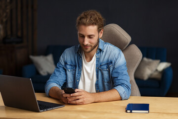 Young man using smartphone and smiling. Happy businessman using mobile phone apps, texting message, browsing internet, looking at smartphone. Concept of young people working with mobile devices.