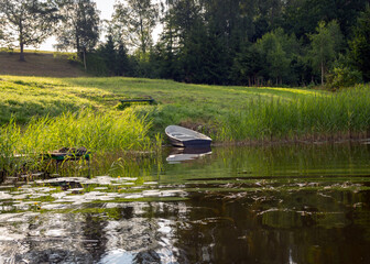 view of the boat on the shore of the lake, reflections in the calm water of the lake, summer