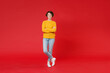© ViDi Studio - Full length of cheerful attractive young brunette woman 20s wearing basic casual yellow sweater standing holding hands crossed looking camera isolated on bright red colour background studio portrait.