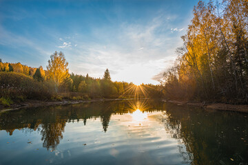 Wall Mural - autumn landscape, a beautiful forest on the banks of the river, the sunlight and the rays through ye