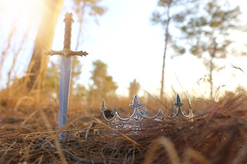 mysterious and magical photo of silver king crown and sword in the England woods. Medieval period concept.