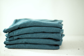 Wall Mural - A stack of t-shirts of the same color on a light background. The minimalistic concept. Space for text.