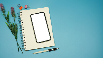 Wall Mural - Flat lay, Workspace back to school and technology education concept on pink table desk with blank screen phone on blank notepad, green plant and stationery, Top view with copy space
