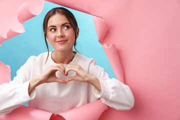 Caucasian young excited woman smiling and gesturing heart shape with fingers