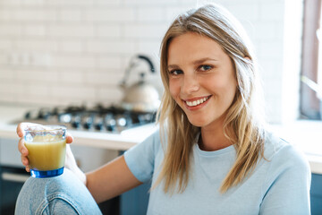 Beautiful joyful girl smiling and drinking juice while having breakfast