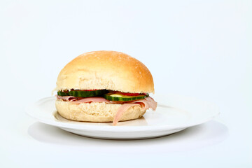  Ham salad in a home baked bread roll with cucumber isolated on a white plate and white background