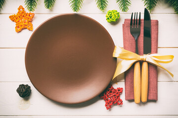 Sticker - Top view of New Year dinner on festive wooden background. Composition of plate, fork, knife, fir tree and decorations. Merry Christmas concept