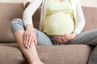© sosiukin - Leg cramps during pregnancy. Closeup of hands massaging swollen foot while sitting on sofa