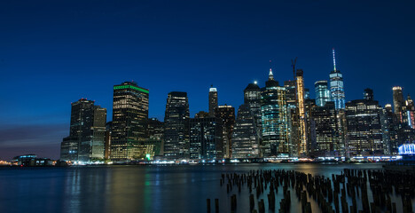 Sticker - Night photo of glowing skyscrapers and a view of Manhattan Bay. Long duration. Panoramic photo. The splendor of the city at night.