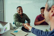 © Prins Productions - Smiling mixed race business man shaking hands with manager accepting project deal sitting in boardroom during team meeting