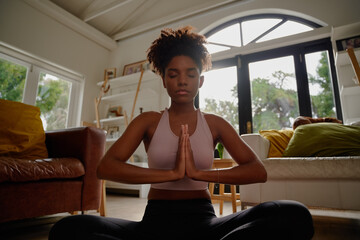 Wall Mural - Portrait of young african yogic woman practicing yoga in namaste position and closed eyes