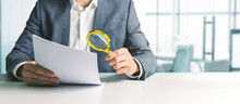Businessman Or Tax Inspector Analyzing Document With Magnifying Glass In Office. Business Financial Audit Concept. Copy Space