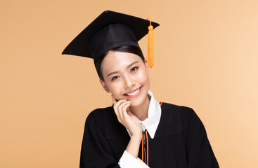 Beautiful Attractive Asian woman graduated in cap and gown smile so proud and happiness,Isolated on Beige background,Education Success Concept