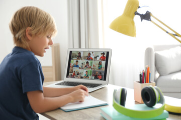 Wall Mural - Little boy studying with classmates via video conference at home. Distance learning during COVID-19 pandemic